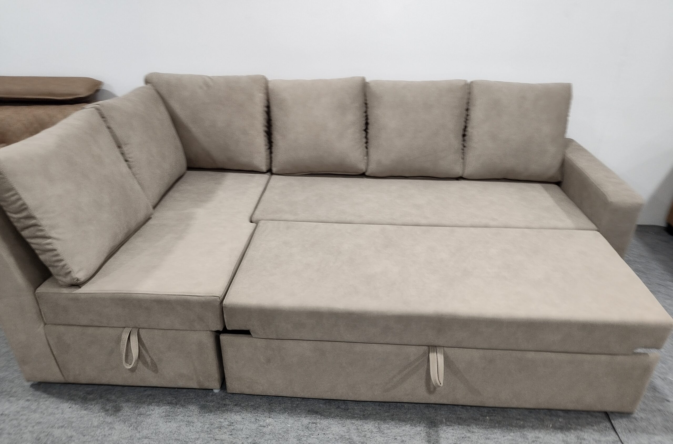 Beige L-shaped sofa cum bed with storage drawers, perfect for modern compact living spaces