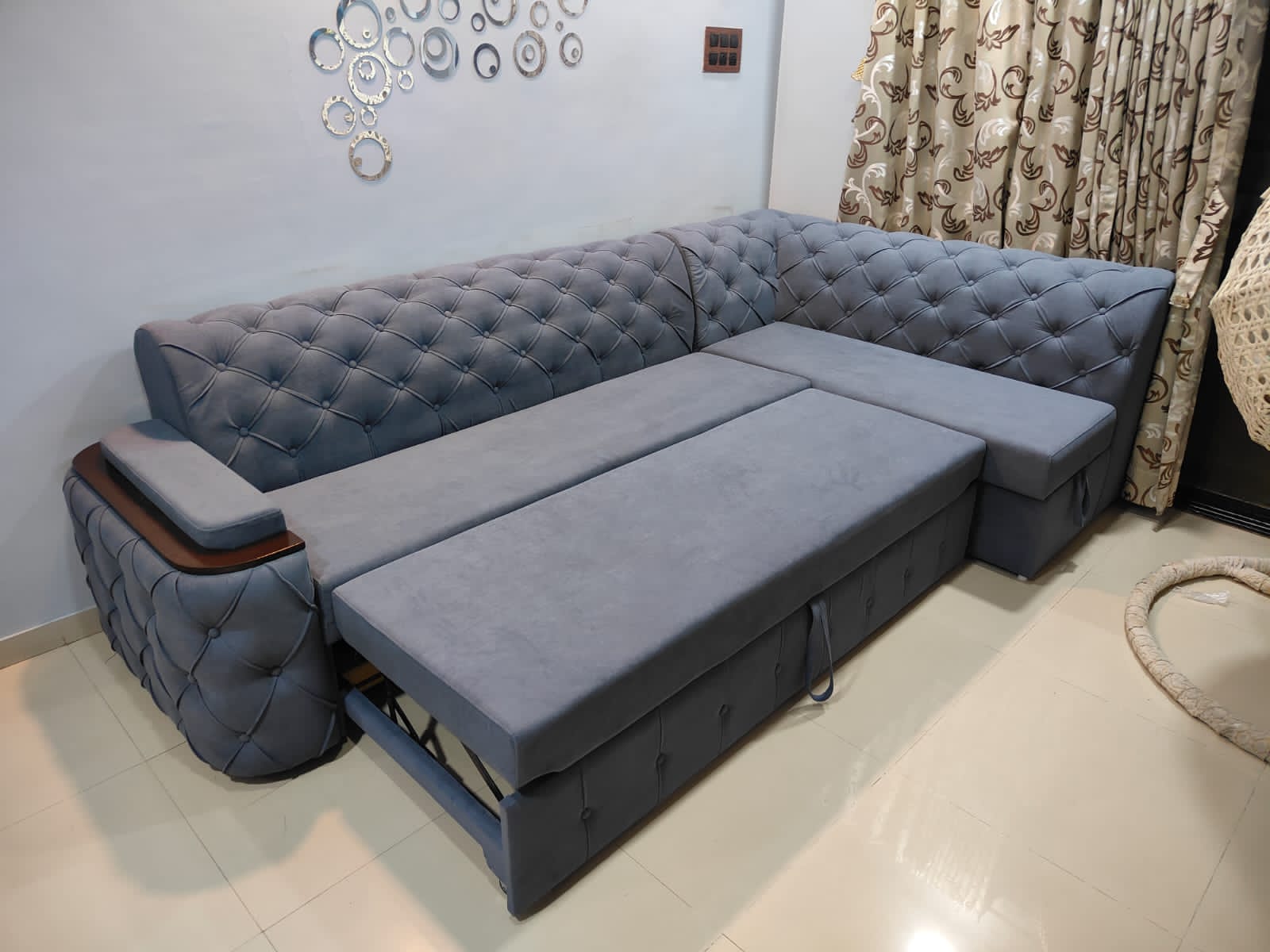 Luxury L-shaped tufted sofa cum bed in grey velvet finish with pull-out extension and armrest tray for elegant living room decor